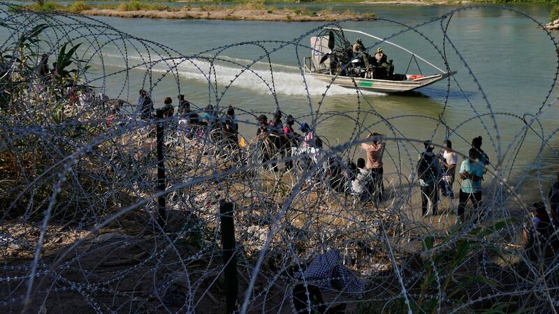 FILE - Migrants who crossed into the U.S. from Mexico are met with concertina wire along the...