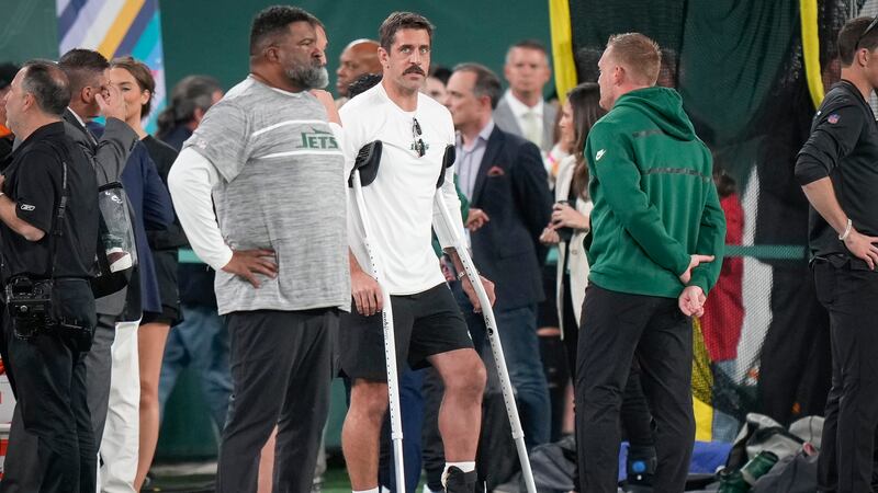 New York Jets quarterback Aaron Rodgers stands on the sidelines before an NFL football game...