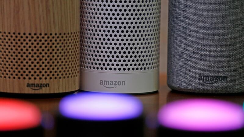 FILE - Amazon Echo and Echo Plus devices, behind, sit near illuminated Echo Button devices...