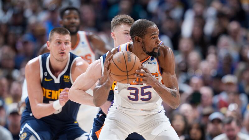 Phoenix Suns forward Kevin Durant, fright, looks to pass the ball as Denver Nuggets guard...